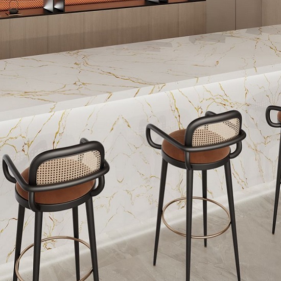 A white quartz worktop with golden veins and two stools